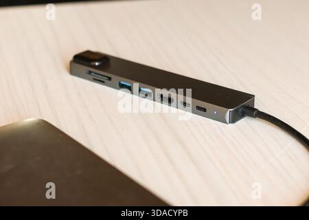 Versatile gray USB-C hub featuring HDMI, USB ports, and SD card reader, connected to a laptop for expanded connectivity Stock Photo