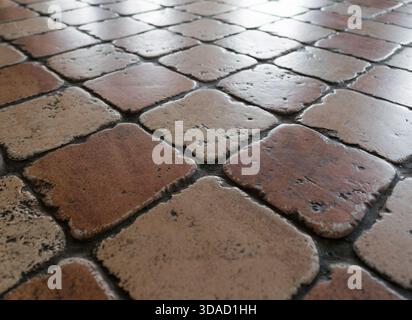 Close-up of a shiny, worn ceramic floor tile showing texture and wear. Perfect background for design and texture purposes Stock Photo