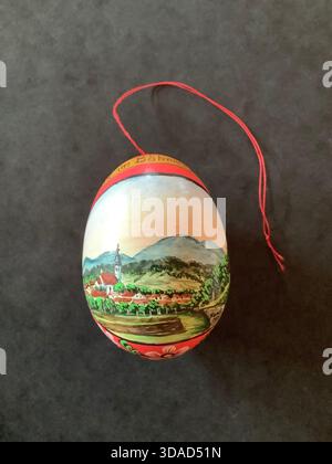 This is a traditional Czech Easter egg hand-painted with a serene Bohemian Forest landscape featuring a village church and rolling hills. Stock Photo