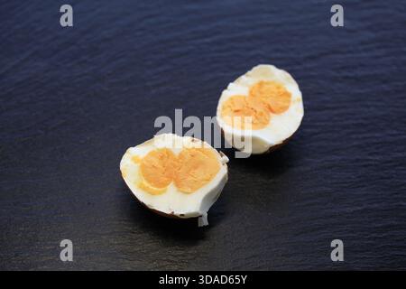 This rare chicken egg has been cracked open to reveal two perfectly formed, bright orange yolks nestled side by side within a single white. Willy Matheisl Stock Photo