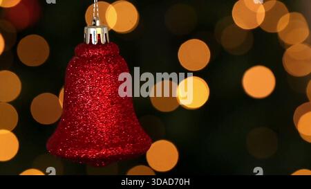 Red glitter bell ornament is hanging in 3D render with silver cap, bokeh lights, business theme Stock Photo