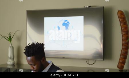Man is sitting at desk in flat design technology workspace, displaying network diagram on screen Stock Photo