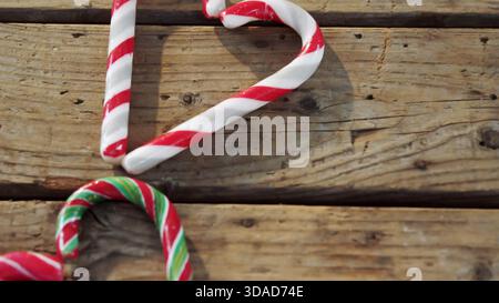 Three candy canes are resting on rustic wooden tabletop in flat design, with business theme Stock Photo