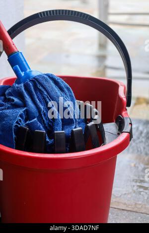 Household cleaning equipment, including a mop and bucket, is photographed in natural light with visible moisture and texture for realistic cleaning co Stock Photo