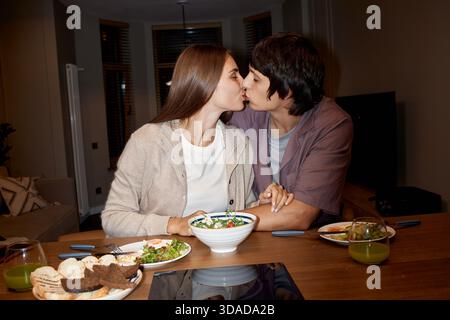 Young Woman and Young Man Kissing While Having Dinner Together Stock Photo
