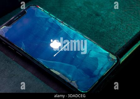 Bajawa, Indonesia - December 9, 2025: Concept of an old iPhone 11 still receiving the latest iOS software update, shown with a cracked screen. Stock Photo