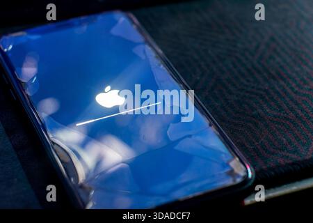 Bajawa, Indonesia - December 9, 2025: Concept of an old iPhone 11 still receiving the latest iOS software update, shown with a cracked screen. Stock Photo