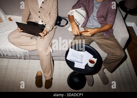 Woman Using Laptop Beside Man Reading Documents Stock Photo