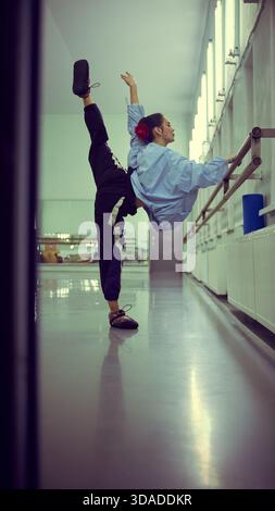 Ballerina stretching at barre during backstage warmup ritual Stock Photo