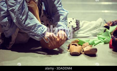 Dancer adjusting shoes on floor as part of stage preparation ritual Stock Photo