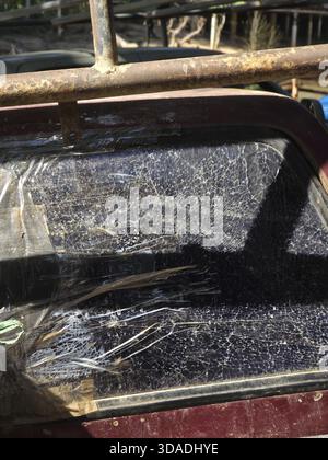 Close up of shattered window on an old, abandoned car. broken glass, rusty metal, and damaged texture convey sense of decay, neglect, and urban grunge Stock Photo