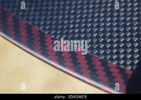 Sleek black and red carbon fiber composite material. This modern abstract background showcases detailed woven texture and geometric pattern ideal for Stock Photo