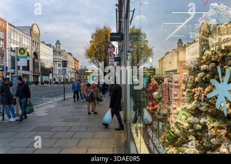 Dublin city centre at holiday time, with reflective shopfronts, festive décor, and bustling pedestrian flow. Stock Photo