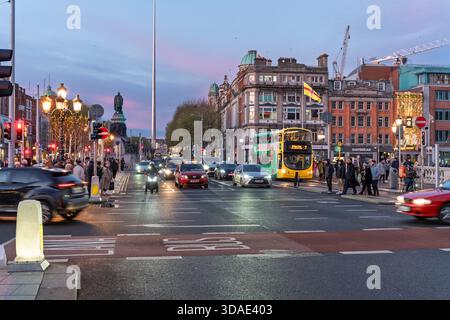 Twilight on Dublin’s iconic O'Connell Bridge, blending historic monuments, busy traffic, and pedestrians in motion Stock Photo