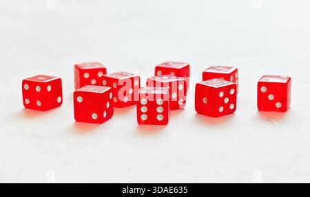Ten red translucent craps dices on white board showing different numbers Stock Photo