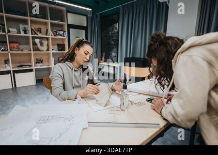 Two design students collaborate at a modern studio, reviewing sketches and building models together Stock Photo