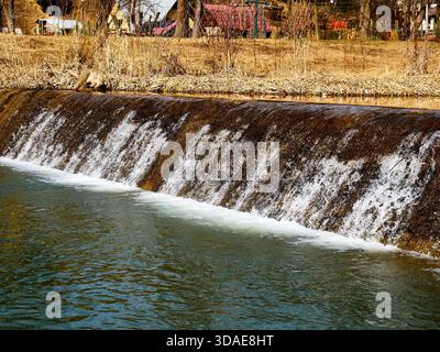 Small waterfall on a river dam with flowing water Stock Photo