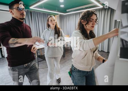 Three friends collaborate in a modern learning space, brainstorming and working on a project Stock Photo