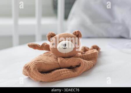 Lovely teddy bear in the white soft baby bed - baby born concept Stock Photo