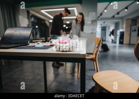 Team collaboration in a modern workspace with a laptop, models, and crafting in progress Stock Photo