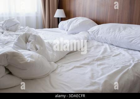 Unmade double bed with white linen in the morning Stock Photo