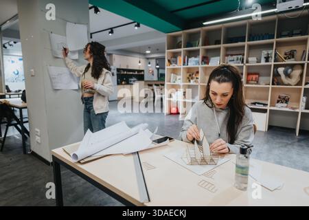 Students collaborate in a modern design studio, building architectural models and refining plans together Stock Photo