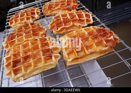 A close up view of several freshly baked Belgian Liege waffles cooling on a metal wire rack. The waffles feature a delicious golden-brown crust with c Stock Photo