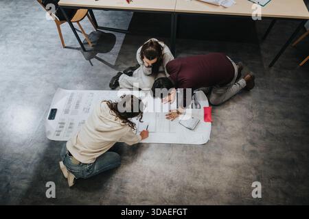 Students collaborate on a large design plan in a modern classroom collaboration center Stock Photo