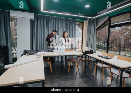 Students collaborate in a modern classroom studio, organizing plans and materials for a group project Stock Photo