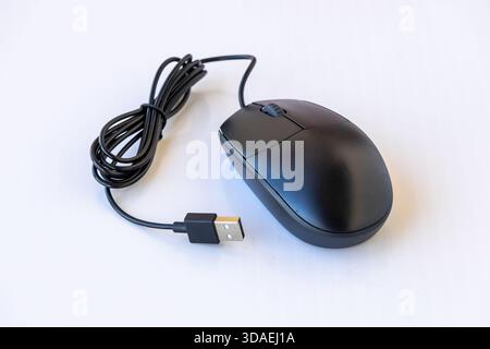 Close-up of a modern, ergonomic black wired optical computer mouse with a scroll wheel and USB connection cord, isolated on a white background. Techno Stock Photo