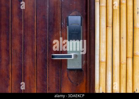 Close-up of a modern electronic hotel door lock (keycard/RFID reader) installed on a polished wooden door, providing keyless entry and enhanced securi Stock Photo
