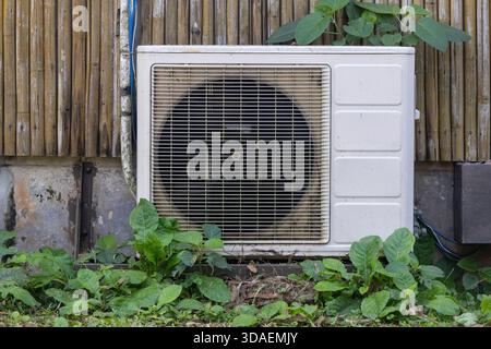 Close-up of an outdoor condenser unit for a home or building's Air Conditioning (AC) or heat pump system, installed adjacent to a structure featuring Stock Photo