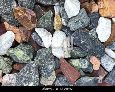A diverse collection of stones in various colors and textures, featuring shades of gray, white, red, and brown. Ideal for natural background or design Stock Photo