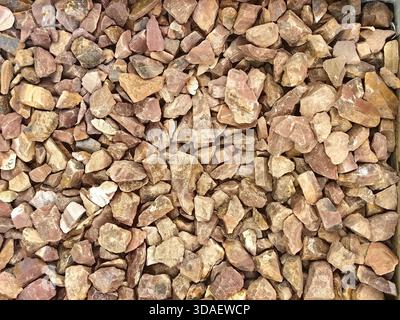 A close-up image showcasing a variety of rough, irregularly shaped pink stones arranged closely together, creating a natural and earthy texture ideal Stock Photo