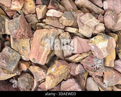 A close-up view of a pile of natural stones displaying a variety of earthy colors, including shades of brown, pink, and orange, creating a rich textur Stock Photo