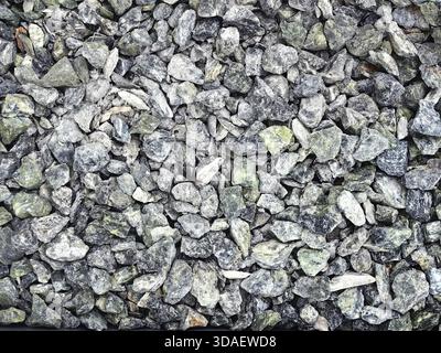 Close-up image showcasing a textured pattern of gray and green stones of varying shapes and sizes. Ideal for natural background designs and landscapin Stock Photo
