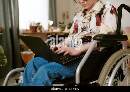 Young Adult Woman with Disability Using Laptop While Working Indoors Stock Photo
