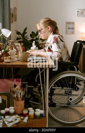 Young Adult Woman with Disability Working at Desk in Wheelchair Stock Photo