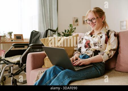 Portrait of Young Adult Woman Smiling While Working Remotely Indoors Stock Photo