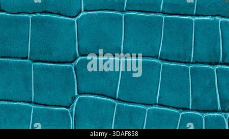 Close-up of teal crocodile leather texture with embossed rectangular pattern, vibrant and tactile. Natural background for luxury design, fashion detai Stock Photo