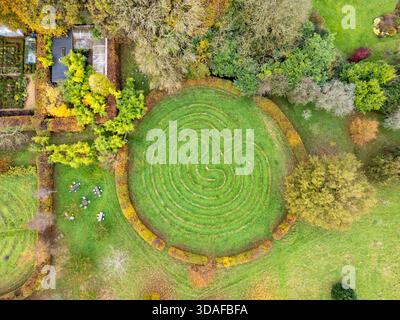 Aerial view of the lush green Kingscote maze, a circular labyrinth embraced by autumnal foliage, creating an intricate pattern from above, Tetbury, En Stock Photo