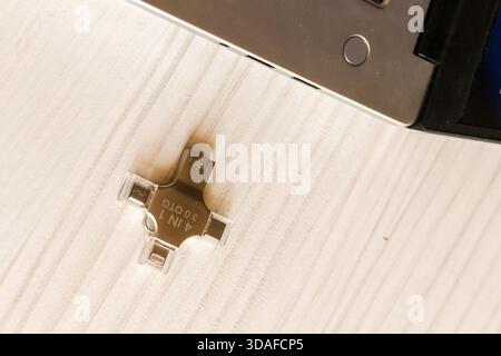 Multi-functional USB drive positioned beside a silver laptop with an open screen on a light wooden table, ready for immediate data connection and use. Stock Photo