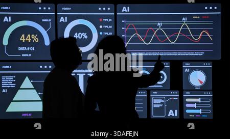 AI Using. Silhouetted analysts interact with a large AI data. AI Display charts graphs and analytics. Business team using futuristic AI interface visu Stock Photo