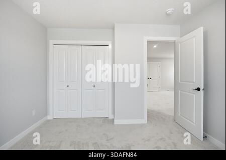 White bedroom with a white door and white closets. The room is empty and has a clean, minimalist look Stock Photo