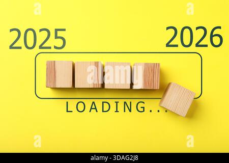 New Year 2026. Wooden cubes in loading bar on yellow background, top view Stock Photo