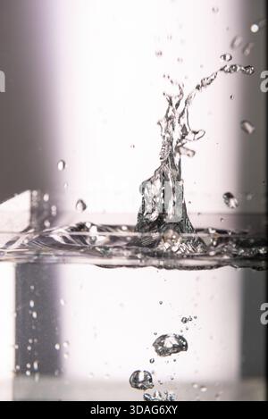 421.A low-angle, close-up photograph capturing the surface of water with ripples and a small splash. The image is lit with a purple light, casting a v Stock Photo