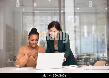 Two multiethnic female coworkers working together at laptop Stock Photo