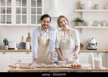 Smiling couple looking at camera distracted from making dumplings Stock Photo