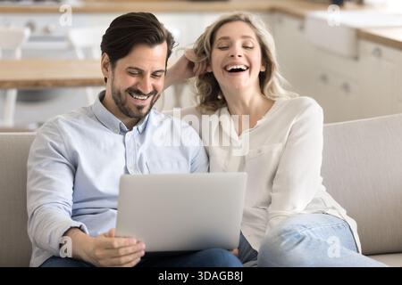 Happy joyful husband wife relaxing enjoying funny movie using notebook Stock Photo