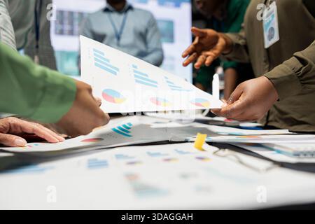 Close up of diverse analysts collaborating on data predictions and projections, exchanging important papers after hours in a meeting. Updating investors with budget and other business intel. Stock Photo